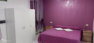 ein lila Schlafzimmer mit einem Bett mit zwei Handtüchern darauf in der Unterkunft Appartamento tra Como e Milano in Bregnano