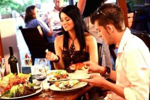 a man and woman at a table with plates of food at Kacy's Bargara Beach Motel in Bargara