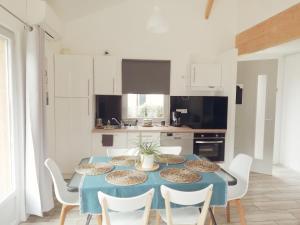 a kitchen with a blue table and white chairs at Maison moderne proche lac et plage in Léon