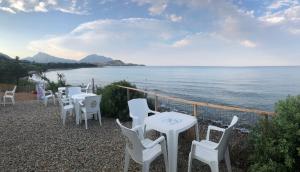 una fila de mesas y sillas blancas junto al océano en Tenda, en Tertenìa