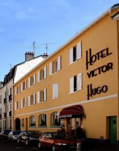 un gran edificio amarillo con un cartel. en Hotel Victor Hugo en Dijon