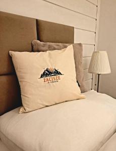 a bed with a pillow with a mountain sign on it at Zacisze w Górach in Sosnówka
