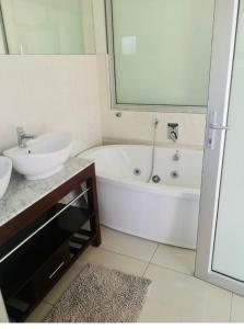 a bathroom with a sink and a bath tub and a sink at Ndaba Golf Lodge on 13th hole in East London