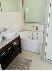 Un baño con lavabo y bañera y un lavabo. en Ndaba Golf Lodge on 13th hole, en East London