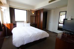 Habitación de hotel con cama y TV de pantalla plana. en Green Rich Hotel Oita Miyakomachi, en Oita