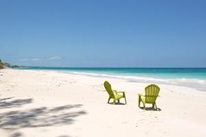 two chairs sitting in the sand on the beach at Tourmaline home in Governorʼs Harbour