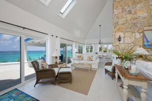 a living room with white furniture and a view of the ocean at Tourmaline home in Governorʼs Harbour