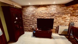 a living room with a tv and a stone wall at Urrondo in Lekeitio
