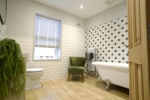 a bathroom with a white tub and a green chair at The Hideout - free parking in Southampton