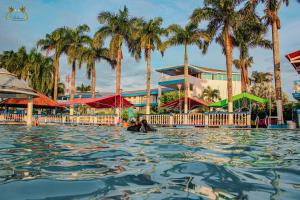 pessoas nadando na água em um resort com palmeiras em Centro Vacacional Las Palmas em San José del Guaviare