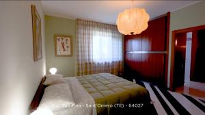 a bedroom with a bed and a chandelier at B&B Villa Tina in SantʼOmero