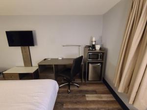 a bedroom with a desk and a bed and a desk with a chair at Travelodge by Wyndham Barrie in Barrie