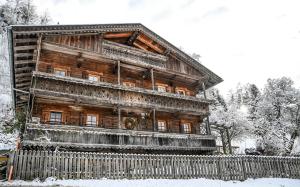 ein altes Holzhaus mit einem Zaun im Schnee in der Unterkunft Haus Prantl in Gallzein