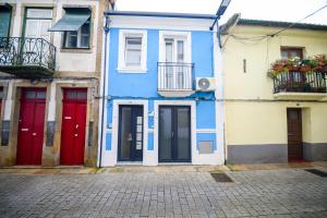 een blauw gebouw met rode deuren op een straat bij Apartamentos do Corgo in Vila Real