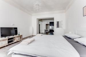プラハにあるLovely Apartments Heart of Pragueの白い大きなベッドルーム(大型ベッド1台、テレビ付)