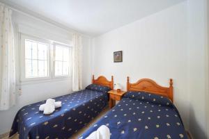 two beds in a bedroom with blue sheets with towels at Apartamento Balcón de San José, piscina, parking in San José +19 photos
