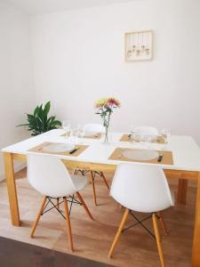 une table à manger avec des chaises blanches et un mur blanc dans l'établissement Maison 2 chambres, 6 pers - Wifi et Linge inclus - Niort centre, à Niort