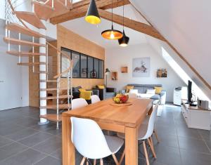 a dining room and living room with a wooden table and white chairs at Magnifique Gite Le Clos des pierres Route des Vins d'Alsace in Beblenheim