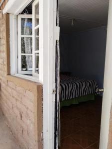 una puerta abierta a una habitación con cama y ventana en Hospedaje Rural Casa de Felix, en San Pedro de Atacama