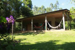 a house with a hammock in front of a yard at Casa de Campo - Sítio da tia Vera in Maquiné