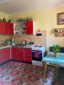 a kitchen with red cabinets and a stove and a table at Ubytovanie u Katky in Bobrovec