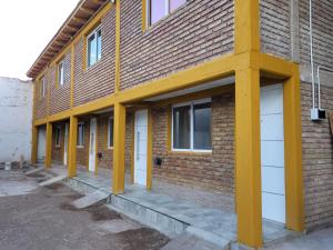 a row of yellow columns on the side of a brick building at La Tranquera Apartamentos in Malargüe