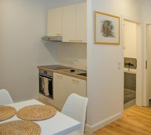 a kitchen with white cabinets and a table and chairs at Pink Lotus Apartment in Vienna