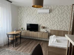 een woonkamer met een televisie en een tafel met een stoel bij Hatvan Central Apartment in Debrecen