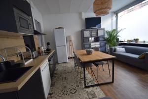 eine Küche und ein Wohnzimmer mit einem Tisch und einem Sofa in der Unterkunft La Maison du Bonheur - Lille in Lille