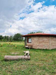 un piccolo edificio in mattoni in un campo con tronchi di Buda de Uco Lodge a Tunuyán