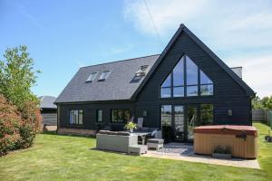 a black house with a table and a bench in a yard at Hurstpierpoint 3 bedroom House with Hot-Tub & Garden in West Sussex in Hurstpierpoint