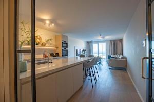 a kitchen with a sink and a living room at By Sea, Full Sea View, balcony, use of hotel Pool and Sauna in Cadzand