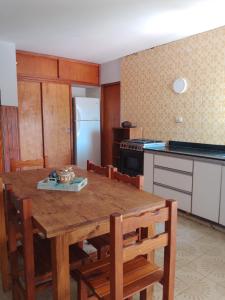 cocina con mesa de madera con sillas y nevera en Tineo en Villa Gesell