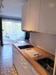 a kitchen with white cabinets and a sink at Estudio BEN NER Salou. in Salou