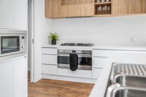 a white kitchen with a stove and a microwave at Julie-Anna, Bendigo in Bendigo