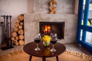 two glasses of wine on a table in front of a fireplace at Topara Hotel Boutique in San Vicente de Cañete