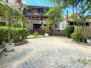a brick courtyard with trees and a building at Praia dos Ossos Guest House - Búzios com pé na areia in Búzios