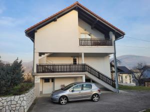 a small car parked in front of a house at Apartman Studenac in Kiseljak