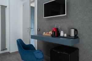 a room with a blue chair and a tv on a wall at MyHouse Pompei in Pompei