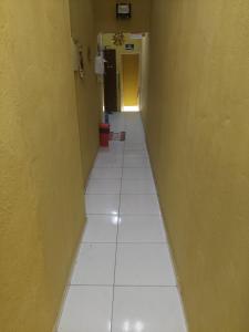 um corredor com piso em azulejo branco e uma parede amarela em Pousada Aconchego de Mãe em Fortaleza