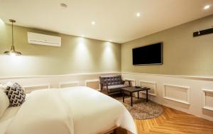 1 dormitorio con 1 cama, 1 silla y TV de pantalla plana en Hotel the Sweet en Busan