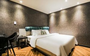 1 dormitorio con cama blanca, escritorio y silla en Hotel the Sweet en Busan