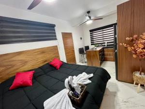 a bedroom with a black bed and red pillows at AHAU Playa in Playa del Carmen