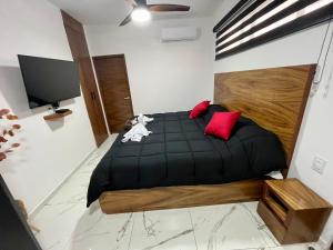 a bedroom with a black bed with red pillows at AHAU Playa in Playa del Carmen