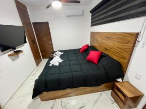 a bedroom with a large black bed with red pillows at AHAU Playa in Playa del Carmen