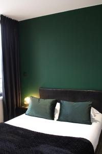 a bedroom with a large bed with a green wall at Résidence "Le Vélodrome" in Maubeuge