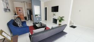ein Wohnzimmer mit einem blauen Sofa und einem TV in der Unterkunft Effortless Self Catering Accommodation in East London