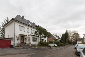 une maison blanche avec une porte rouge dans une rue dans l'établissement Apartment Wilhelmstr für bis zu 3 Personen, à Brühl