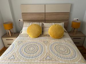 een bed met 2 gele kussens en 2 lampen bij Apartamento Ría de Arousa in Boiro