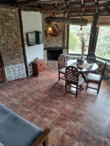 Habitación con mesa, sillas y chimenea. en Cabañas El Molino en Potrerillos